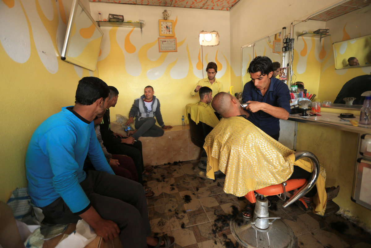 Iraqi men are seen at a barber shop in Intisar district of Mosul, Iraq, November 14, 2016. REUTERS/Ari Jalal