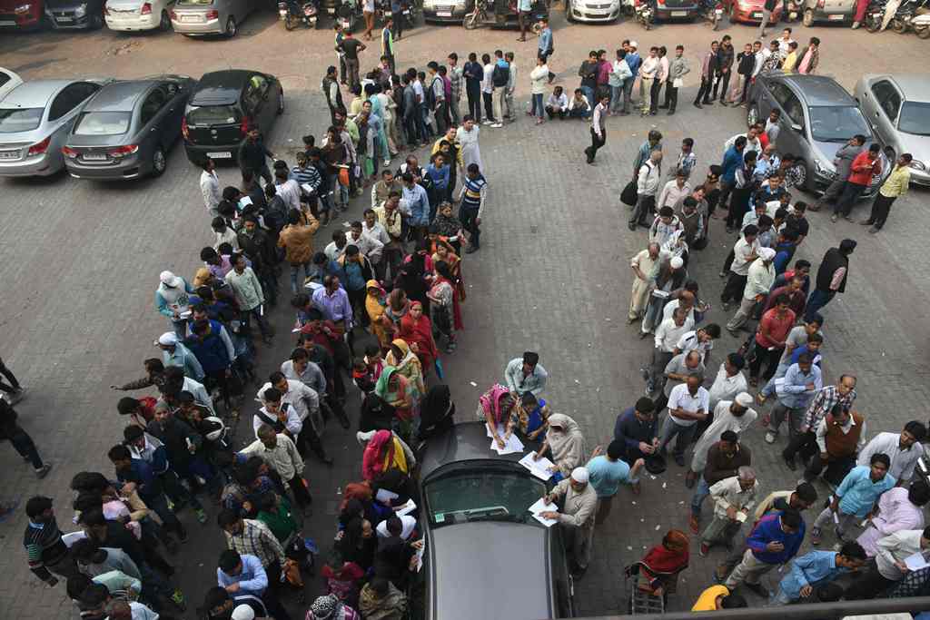 Indian customers form queues outside banks to deposit and exchange old denomination Indian rupee 500 and 1000 currency notes for new ones, in New Delhi on November 15, 2016. AFP / DOMINIQUE FAGET