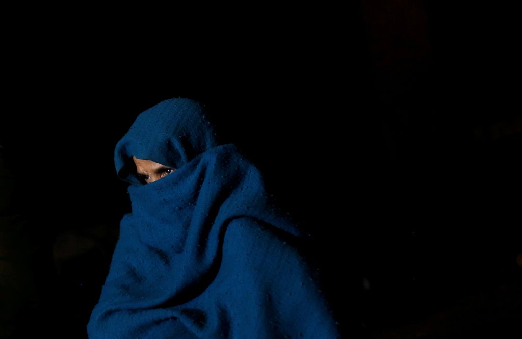 A woman wrapped in a blanket sits on a footpath as she waits for the bank to open to exchange her old high-denomination banknotes in the early hours, in the old quarters of Delhi, India, November 16, 2016. REUTERS/Adnan Abidi 