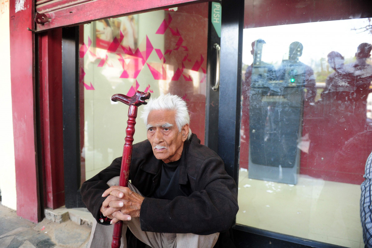 An elderly Indian man, who arrived four hours earlier, waits outside an empty ATM at a bank in Allahabad on November 16, 2016. Long queues formed outside banks in India since the government's shock decision to withdraw the two largest denomination notes f