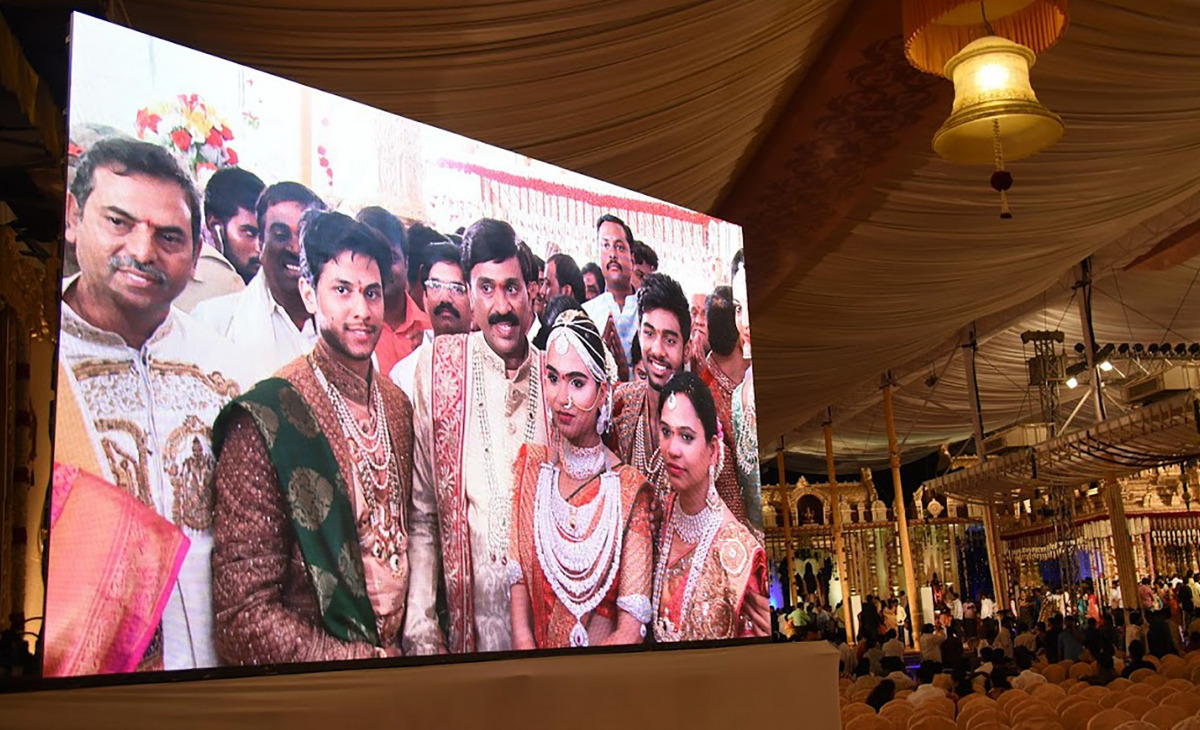 Indian mining tycoon, Gali Janardhan Reddy, (C) is seen on a big screen as he poses with his daughter Bramhani (2R) and son-in-law, Rajeev Reddy (2L) during their wedding at the Bangalore Palace Grounds in Bangalore. (AFP)