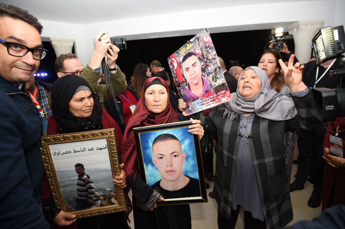 Tunisian mothers of a torture victims carry their sons' portraits as they arrive for a hearing before the The Truth and Dignity Commission (IVD) in Tunis on November 17, 2016. Victims of murder, rape and torture under successive dictatorships started test