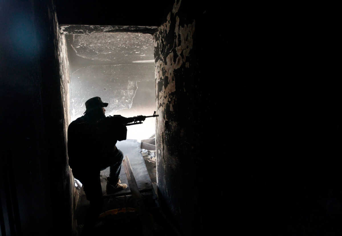 A fighter of Libyan forces allied with the U.N.-backed government aims his weapon as he takes up position inside a ruined house at the front line of fighting with Islamic State militants in Ghiza Bahriya district in Sirte, Libya November 9, 2016. Picture 