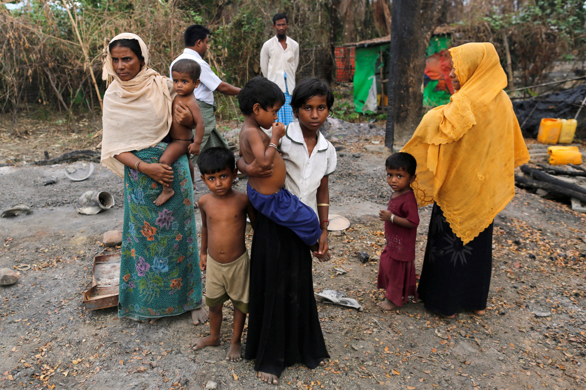 A family stands beside remains of a market which was set on fire, in Rohingya village outside Maungdaw, in Rakhine state, Myanmar October 27, 2016. REUTERS/Soe Zeya Tun