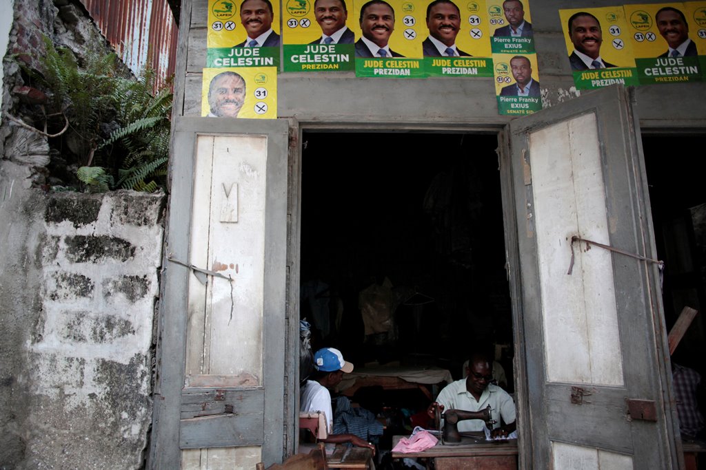 A tailor works in a workshop with posters of presidential candidate Jude Celestin of LAPEH (Alternative League for Progress and Emancipation of Haiti) on the facade, before the election in a street of Les Cayes, Haiti, November 19, 2016. REUTERS/Andres Ma