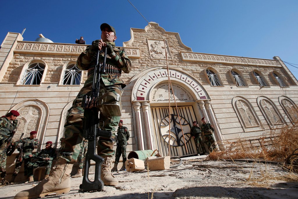 Peshmerga forces stand guard during a procession to erect a new cross over the Mar Korkeis church, after the original cross was destroyed by Islamic State militants, in the town of Bashiqa, Iraq, November 19, 2016. REUTERS/Azad Lashkari