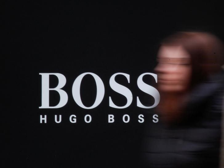 A woman walks past Hugo Boss store logo on a shopping center at the outlet village Belaya Dacha outside Moscow, Russia, April 23, 2016. REUTERS/Grigory Dukor