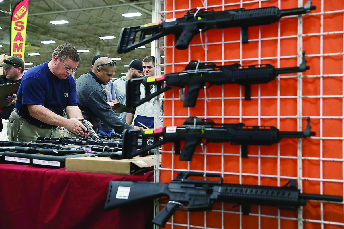 Potential buyers try out guns which are displayed on an exhibitor’s table during the Nation’s Gun Show in Virginia. 