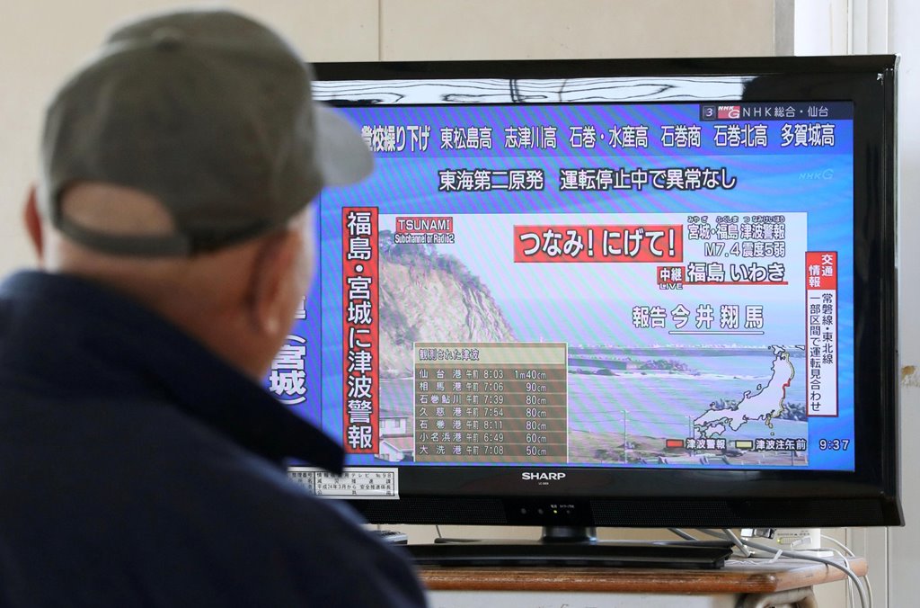 A man evacuated from his home looks at a television screen showing a news report on tsunami warnings, at a shelter following an earthquake, in Sendai, Japan, in this photo taken by Kyodo November 22, 2016. Kyodo via Reuters 