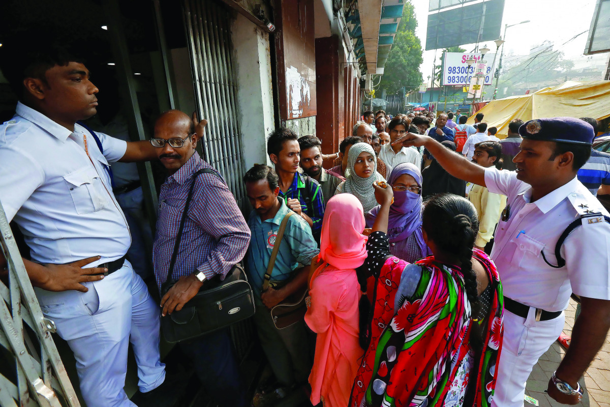 A police officer speaking with people as they queue outside a bank in Kolkata, yesterday.