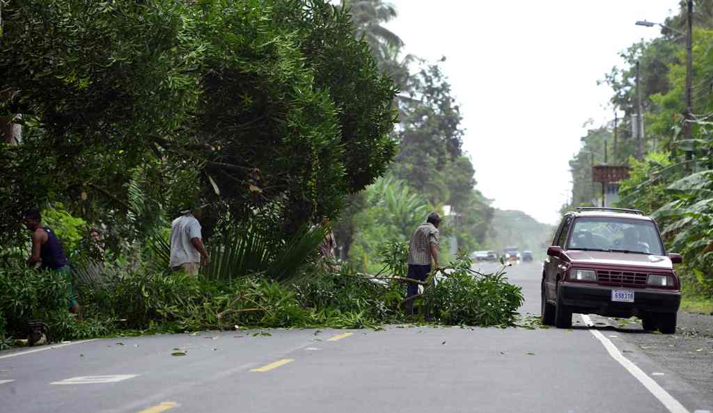 People remove a fallen tree from the road in Cienaguita, Limon, 160 kilometres east of San Jose, where the arrival of Hurricane Otto is expected in Costa Rica, on November 24, 2016.  AFP / EZEQUIEL BECERRA
