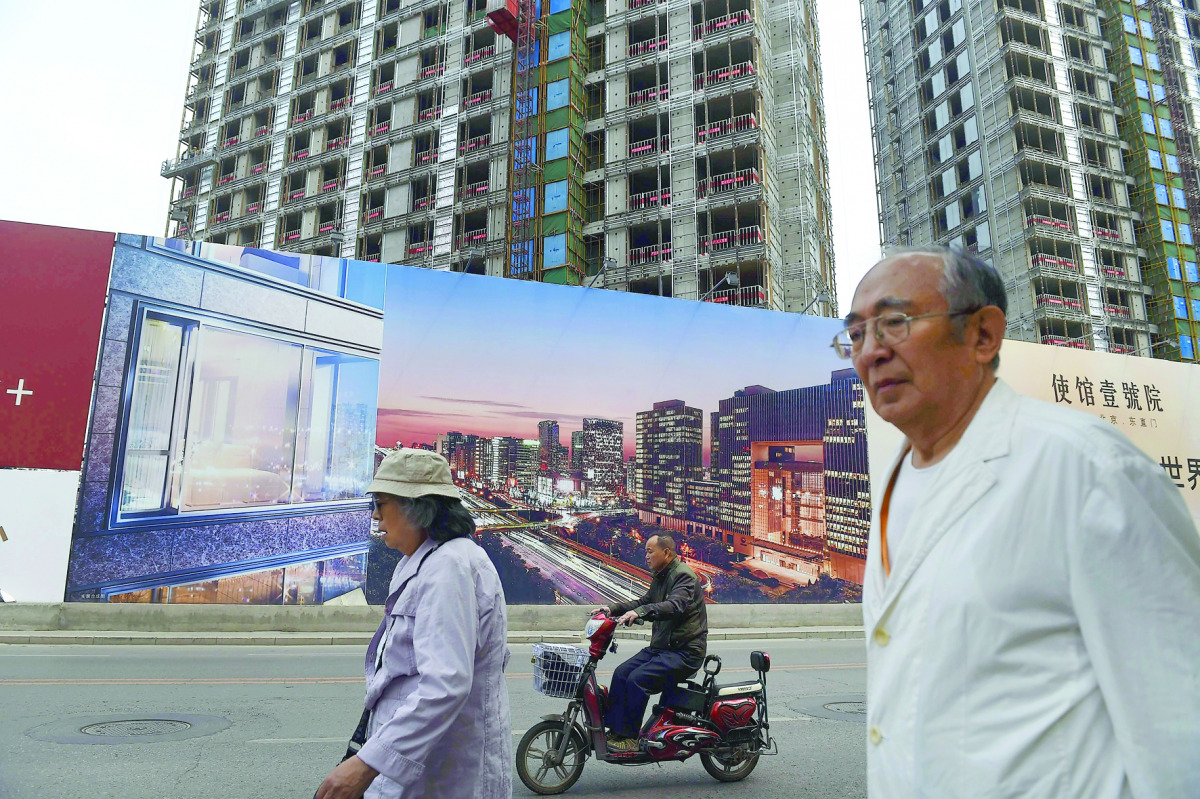 People walking past a billboard advertising a new housing complex outside a construction site in Beijing.