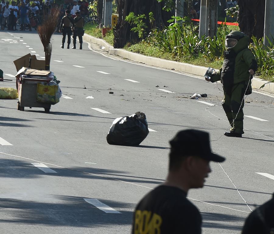 A member of police bomb disposal unit (R) holding a water bomb disruptor, walks towards the site where a suspicious package was found, for detonation along Roxas boulevard near the US embassy in Manila on November 28, 2016. AFP / TED ALJIBE