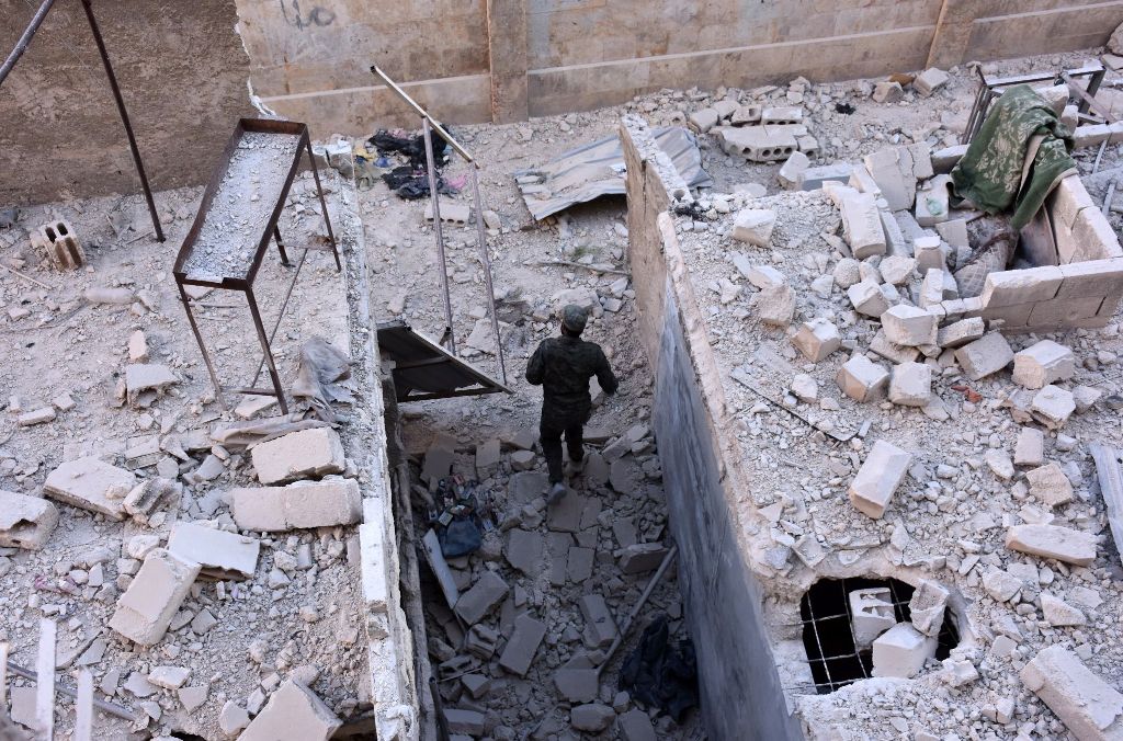 A member of Syrian pro-government forces inspects an area on November 27, 2016 in the Masaken Hanano district in eastern Aleppo, a day after they resized it from rebel fighters.  AFP / GEORGE OURFALIAN
