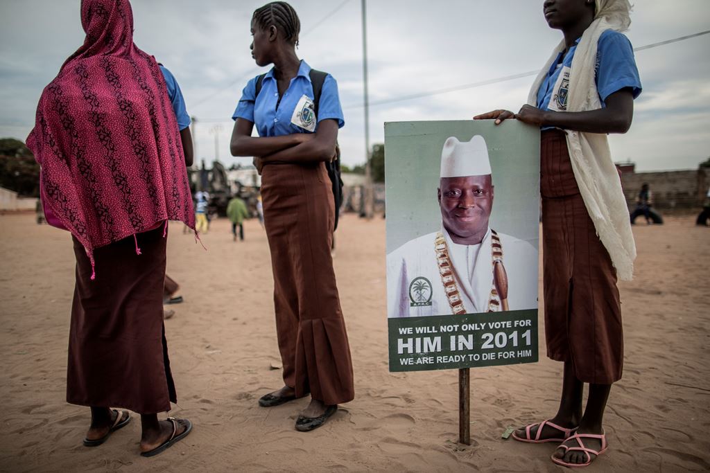 School girls, supporting the Gambian incumbent president Yahya Jammeh, stand by a placard picturing him as the y wait for the start of an electoral meeting in Schur Alagie on November 28, 2016. AFP / MARCO LONGARI