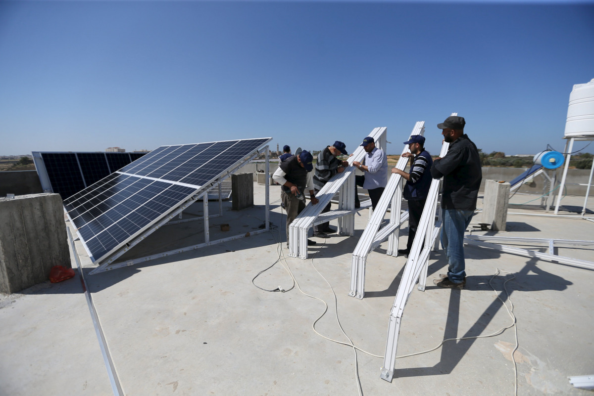 Palestinian workers install solar panels atop the roof of a medical centre in Gaza City, March 1, 2016 (REUTERS / Ibraheem Abu Mustafa) 