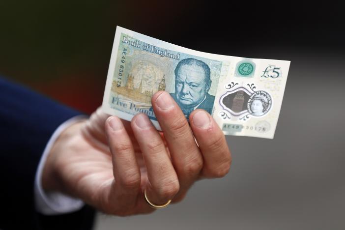 Bank of England governor Mark Carney poses with a new polymer five pound note at Whitecross Street Market in London, Britain September 13, 2016. (REUTERS/Stefan Wermuth/File Photo)