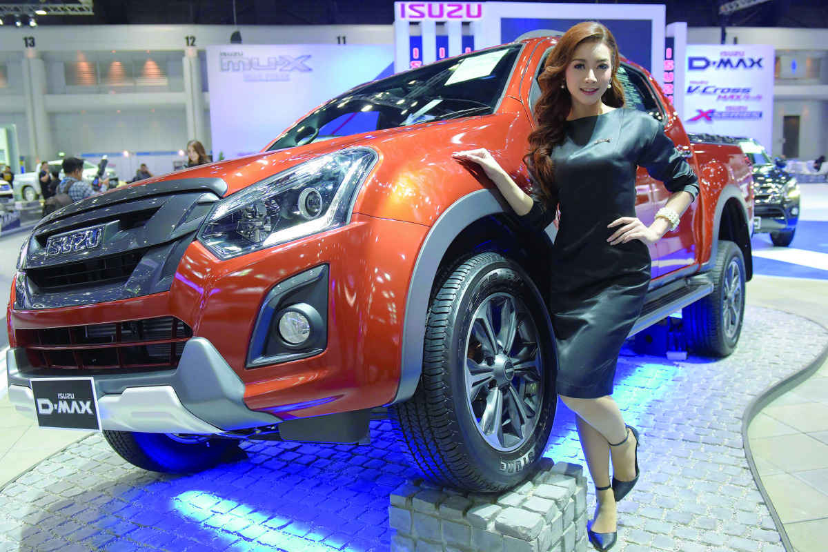 A Thai model poses next to a Isuzu D-MAX pickup truck during the Motor Expo 2016 in Bangkok on December 1, 2016. / AFP / TANG CHHIN SOTHY