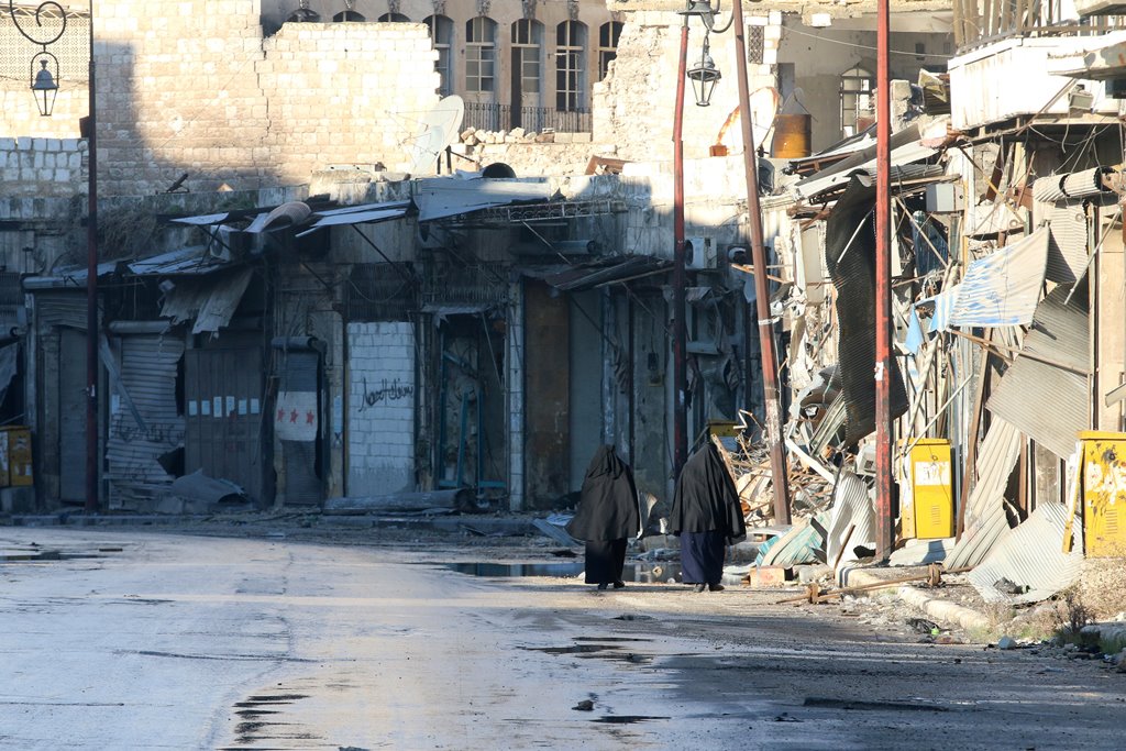 Women walk near damaged buildings in rebel-held besieged old Aleppo, Syria December 2, 2016. REUTERS/Abdalrhman Ismail
