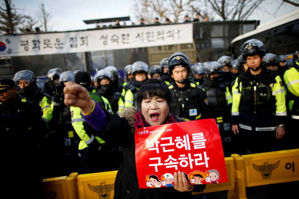 A woman chants slogans in front of riot policemen as they march toward the Presidential Blue House during a protest calling for South Korean President Park Geun-hye to step down in central Seoul, South Korea, December 3, 2016. The sign reads: 