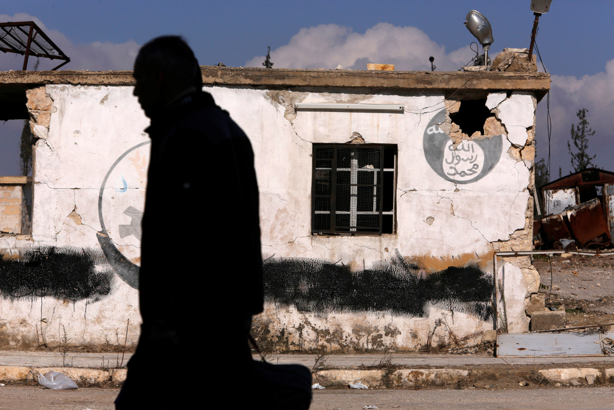 A man walks near a damaged Islamic State sign in government controlled Hanono housing district in Aleppo, Syria December 4, 2016. REUTERS/Omar Sanadiki