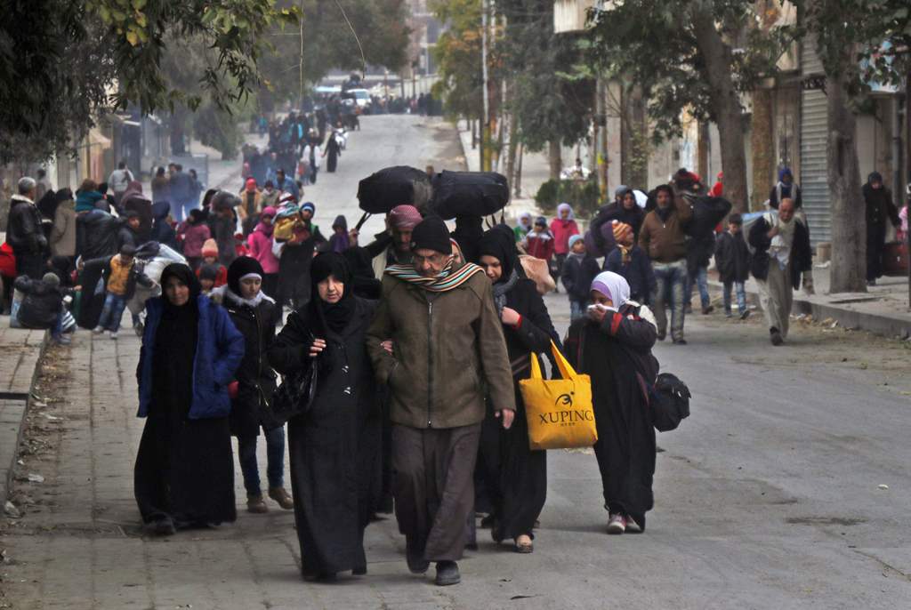 Syrian residents of eastern rebel-held parts of Aleppo walk through the Kadi Askar district as they leave their homes for a safer place in a distinct rebel-controlled area on November 30, 2016, during a Syrian army offensive on the eastern sectors of the 