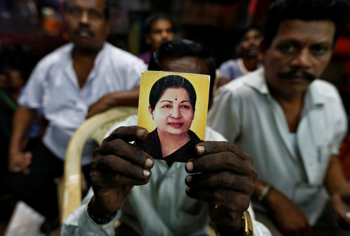 A supporter of Tamil Nadu Chief Minister Jayalalithaa Jayaraman holds her photo at the AIADMK party office in Mumbai, India, December 5, 2016. REUTERS/Danish Siddiqui
