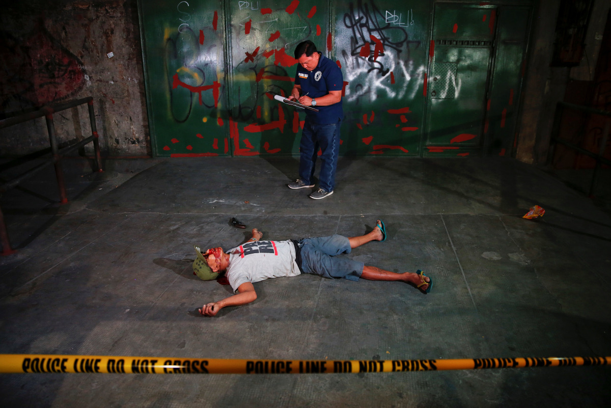  An investigator takes notes next to the body of a man killed in a shoot-out with police in Manila Philippines early October 21 2016