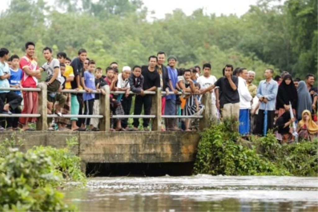 People watch as rescue workers search for two boys who went missing during a flash flood in the southern Thai province of Pattani, on December 6, 2016. - AFP