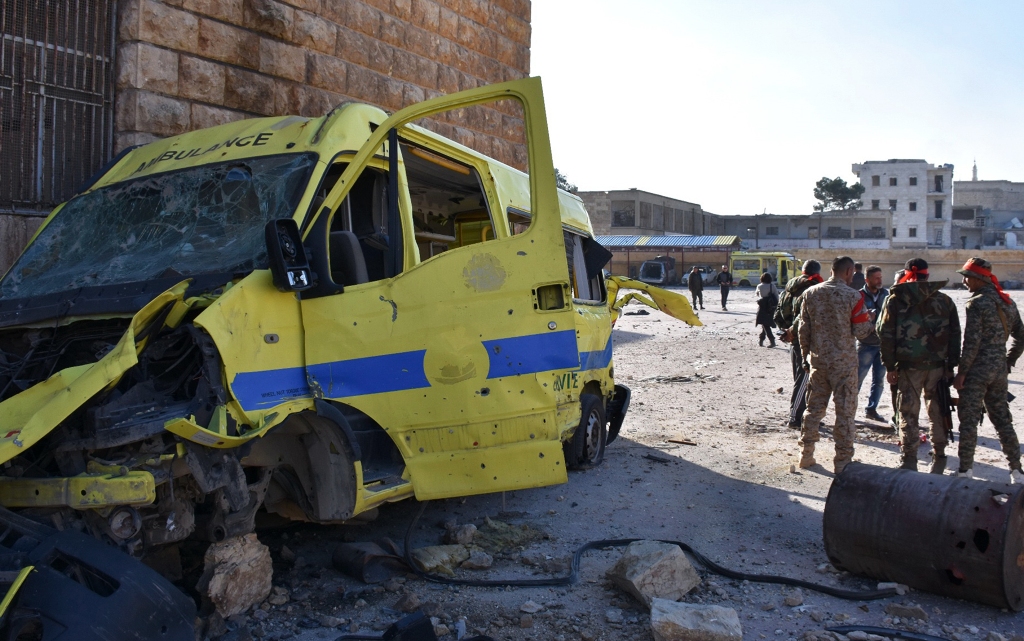 Syrian pro-government forces stand next to the wreckage of an ambulance outside a makeshift hospital which was used by rebel fighters in Aleppo's al-Sakhur neighbourhood, on December 6, 2016, a few days after the area was retaken by the government troops.