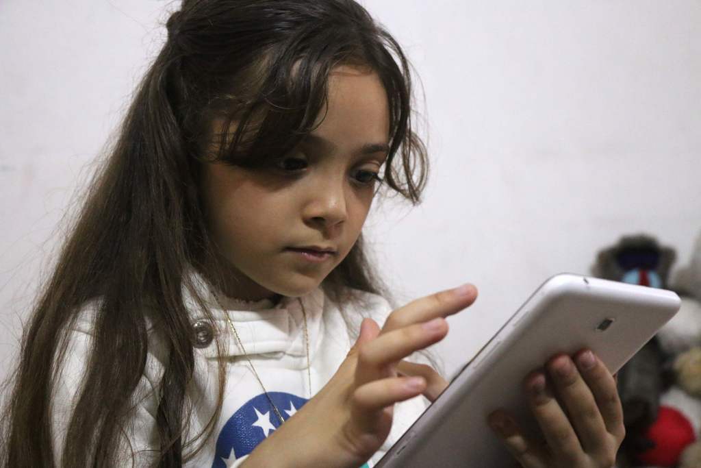 Syrian Bana al-Abed, who with the help of her mother had been posting heartrending tweets in English on life in the besieged eastern districts of Syria's Aleppo, uses a smart-phone to check her Twitter account in her home in east Aleppo, on October 12, 20
