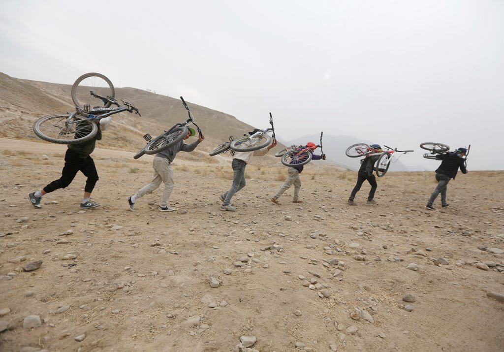 Young Afghan cyclists carry their bicycles on their back on a hill during an exercise on the outskirts of Kabul, Afghanistan November 20, 2016. REUTERS/Omar Sobhani
