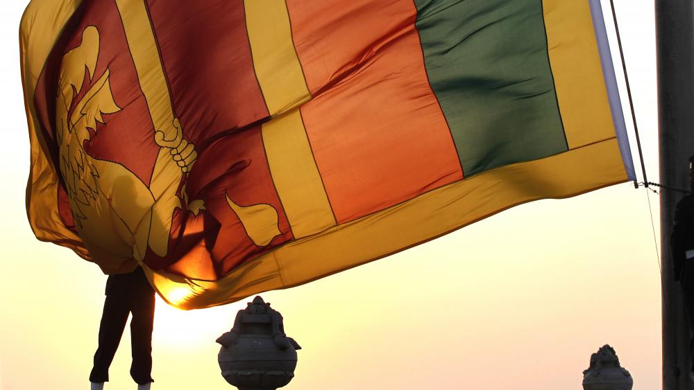 An air force officer holds Sri Lanka's national flag as the sun sets at Galle Face Green in Colombo February 2, 2013. REUTERS/Dinuka Liyanawatte