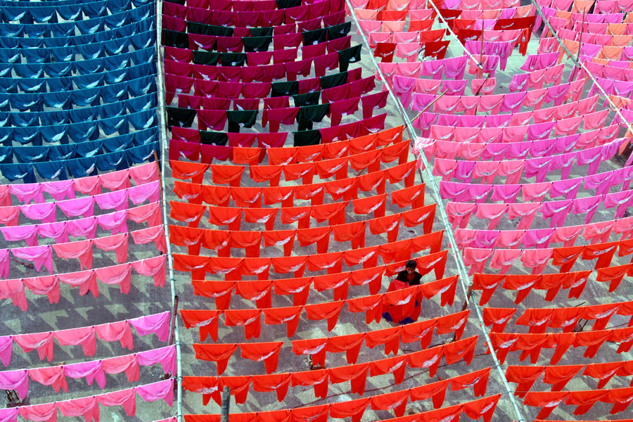 A worker hangs clothes to dry on the roof of a garment factory in Dhaka in this June 15, 2005 file photo. REUTERS/Rafiqur Rahman/Files

