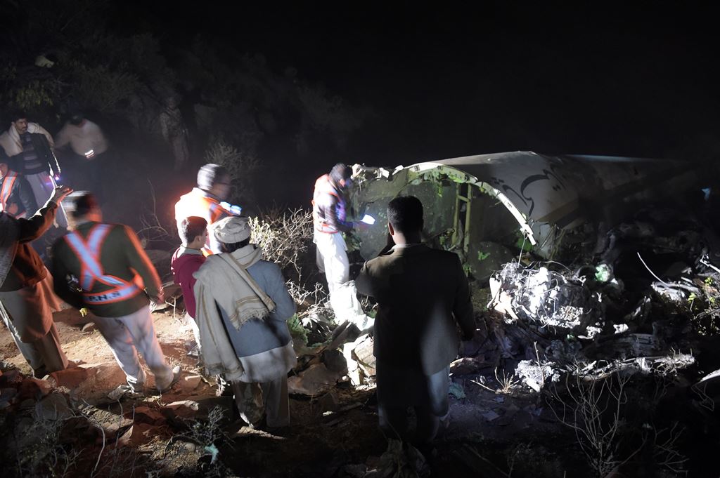 Pakistani residents stand beside the wreckage of the crashed PIA passenger plane Flight PK661 at the site in the village of Saddha Batolni in the Abbottabad district of Khyber Pakhtunkhwa province on December 7, 2016. AFP / AAMIR QURESHI