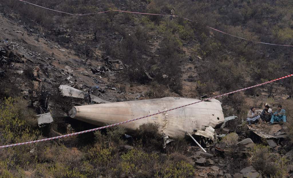 Pakistani sit beside the wreckage of the crashed PIA passenger plane Flight PK661 near the village of Saddha Batolni in the Abbottabad district of Khyber Pakhtunkhwa province on December 8, 2016. AFP / AAMIR QURESHI