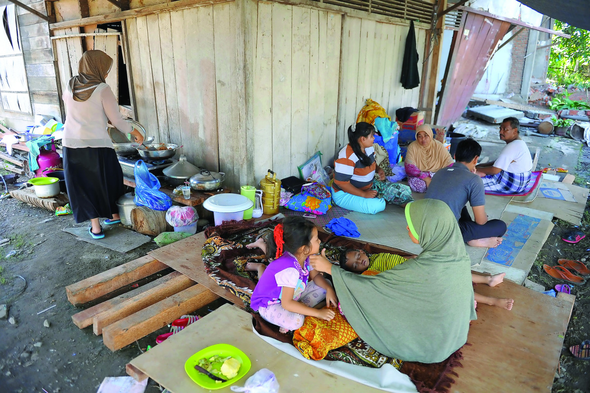 Villagers rest outside their houses which were damaged after an earthquake in Kuta Pangwa village in Pidie Jaya, yesterday.