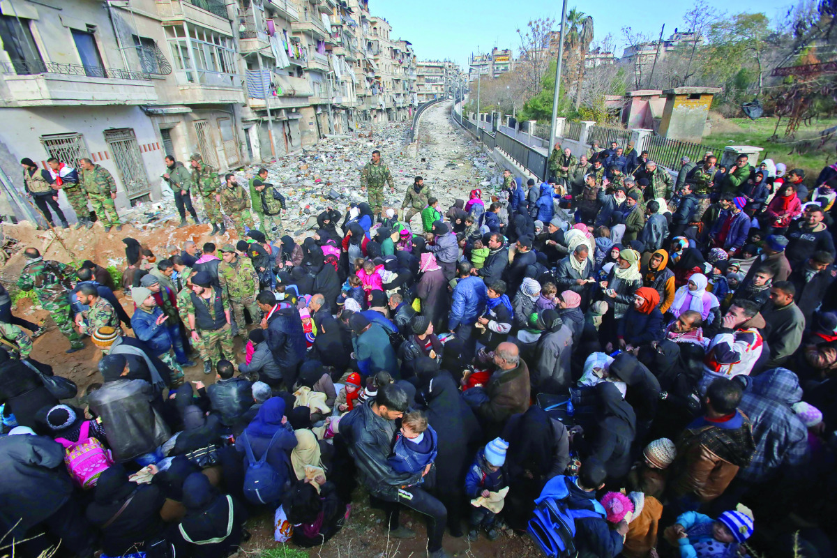 Syrian residents fleeing the violence gather at a checkpoint, manned by pro-government forces, in the Maysaloun neighbourhood of the northern embattled city of Aleppo