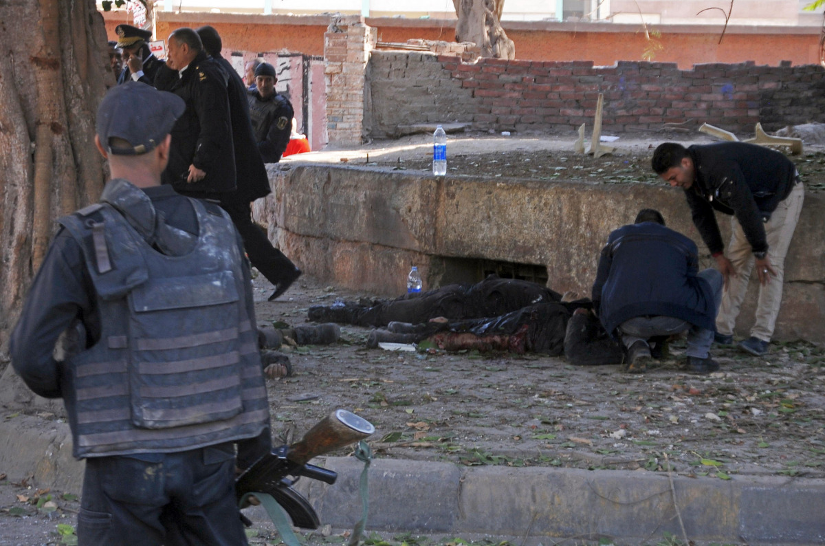 Egyptian security forces check a body at the site of a bomb attack next to a police checkpoint in the western Talibiya district of the capital Cairo on December 9, 2016. AFP