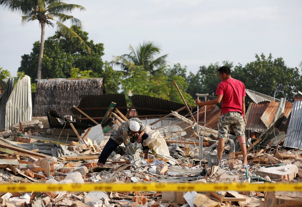 Men look for items to salvage from a building which collapsed following this week's strong earthquake in Pidie Jaya, Aceh province, Indonesia December 10, 2016. REUTERS/Darren Whiteside
