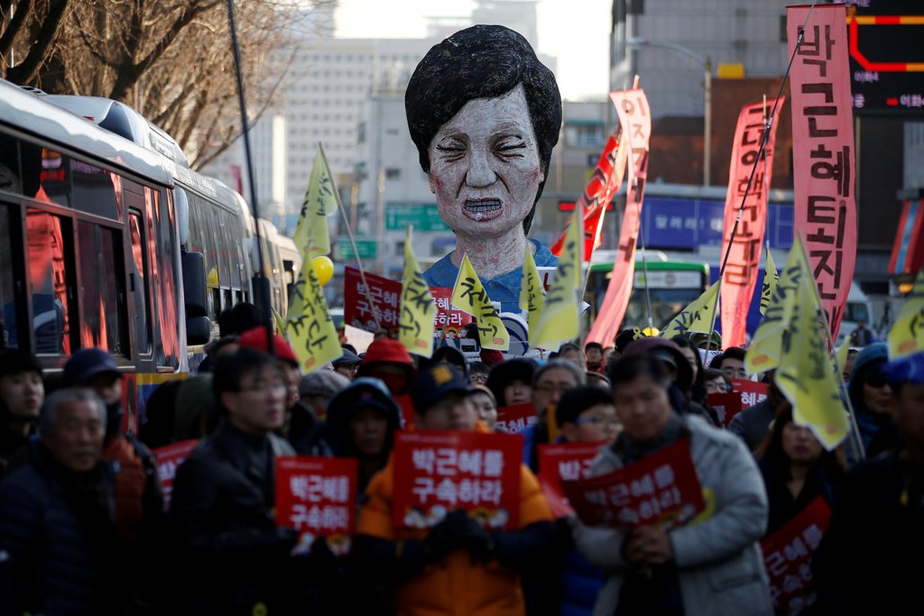 An effigy of South Korean President Park Geun-hye is seen behind people marching towards the Presidential Blue House during a protest calling for South Korean President Park Geun-hye to step down in central Seoul, South Korea, December 10, 2016. The signs