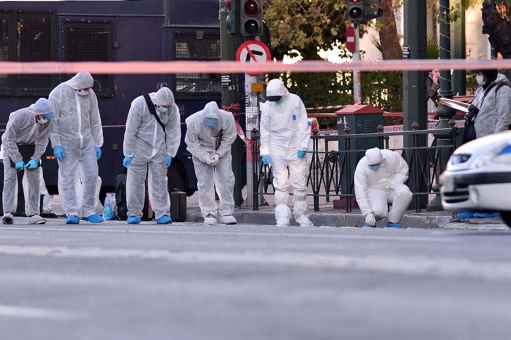 Police officers conduct a search at the front of the French embassy after two motorcyclists threw a hand grenade injuring the guard in central Athens on November 10, 2016 (AFP Photo/Louisa Gouliamaki)