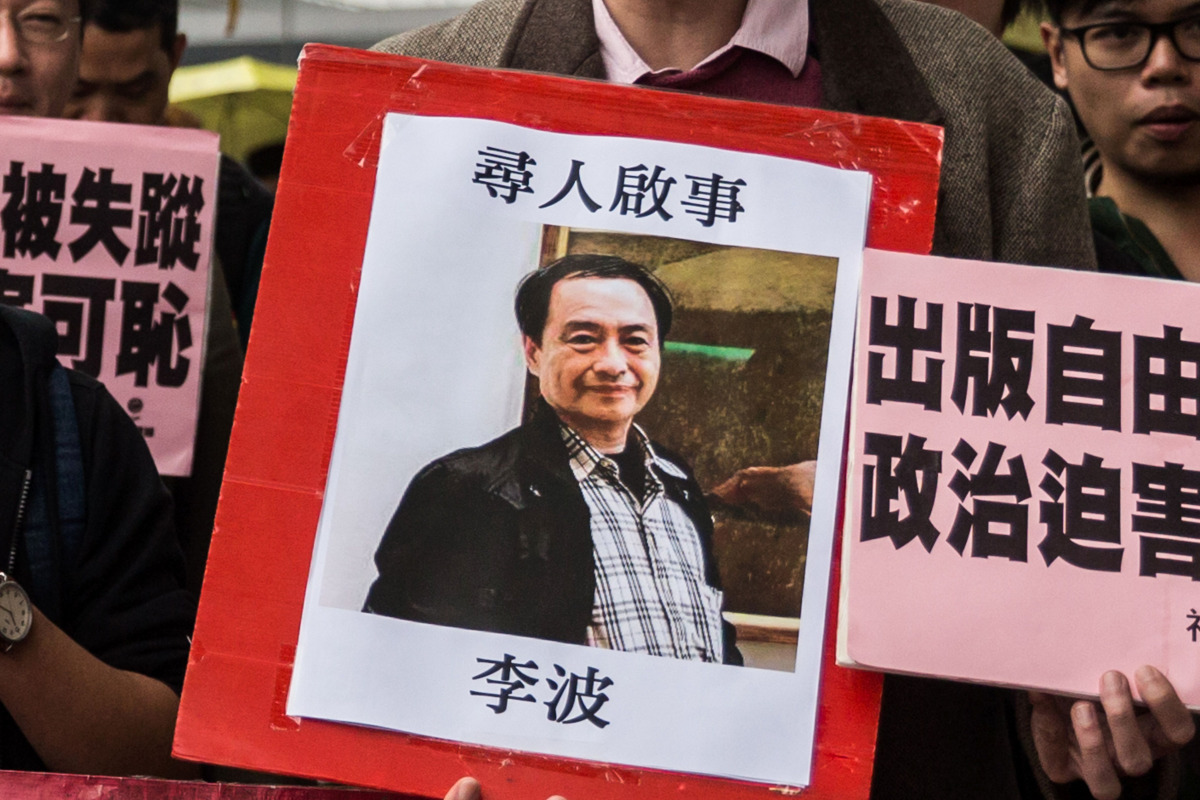 FILE PHOTO: A protestor holding up a missing person notice for Lee Bo 65 as they walk towards China Liaison Office in Hong Kong, January 3, 2016 (AFP / ANTHONY WALLACE) 