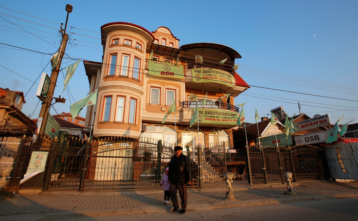 A man walks next to a house decorated with party flags in Suto Orizari, a district with Europe's largest Roma communities, Macedonia, December 7, 2016. Picture taken December 7, 2016. Thomson Reuters Foundation/Ognen Teofilovski