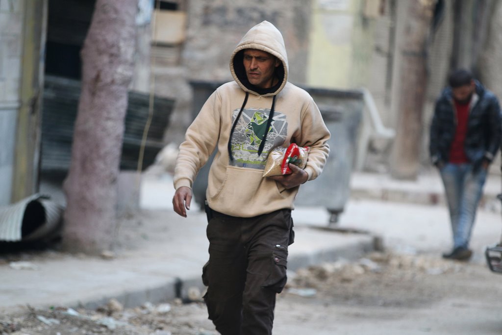 A man carries food as he walks along a street in a rebel-held besieged area of Aleppo, Syria December 10, 2016. REUTERS/Abdalrhman Ismail
