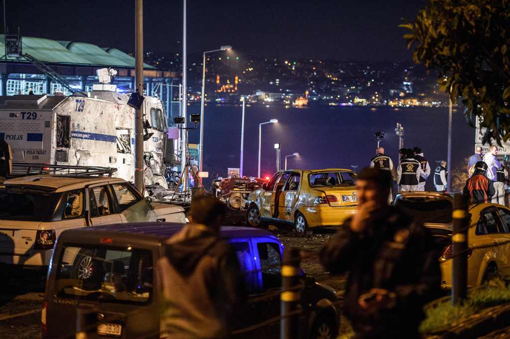 Turkish police officers and forensic work next to damaged police vehicles and cars on the site where a car bomb exploded near the stadium of football club Besiktas in central Istanbul on December 10, 2016. The car bomb exploded in the heart of Istanbul on