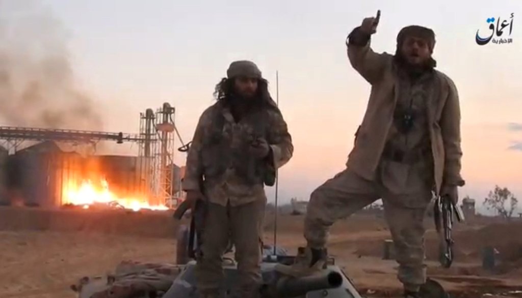 A still image taken from a video released by Islamic State-affiliated Amaq news agency, said to be in Palmyra, on December 11, 2016, purports to show Islamic State fighters in front of silos on fire and said to have been taken over by them. 