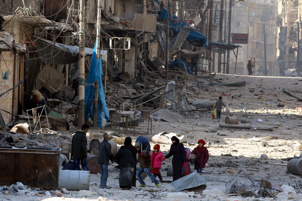 Syrians walk over rubble of damaged buildings, while carrying their belongings, as they flee clashes between government forces and rebels in Tariq al-Bab and al-Sakhour neighborhoods of eastern Aleppo towards other rebel held besieged areas of Aleppo, Syr