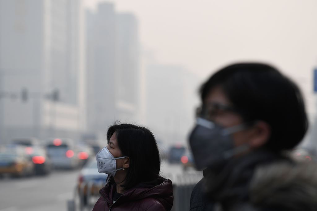 Pedestrians wear masks on a polluted day in Beijing on December 12, 2016. Authorities issued a yellow alert on December 11 for pollution in areas of northern China, including Beijing. / AFP / GREG BAKER

