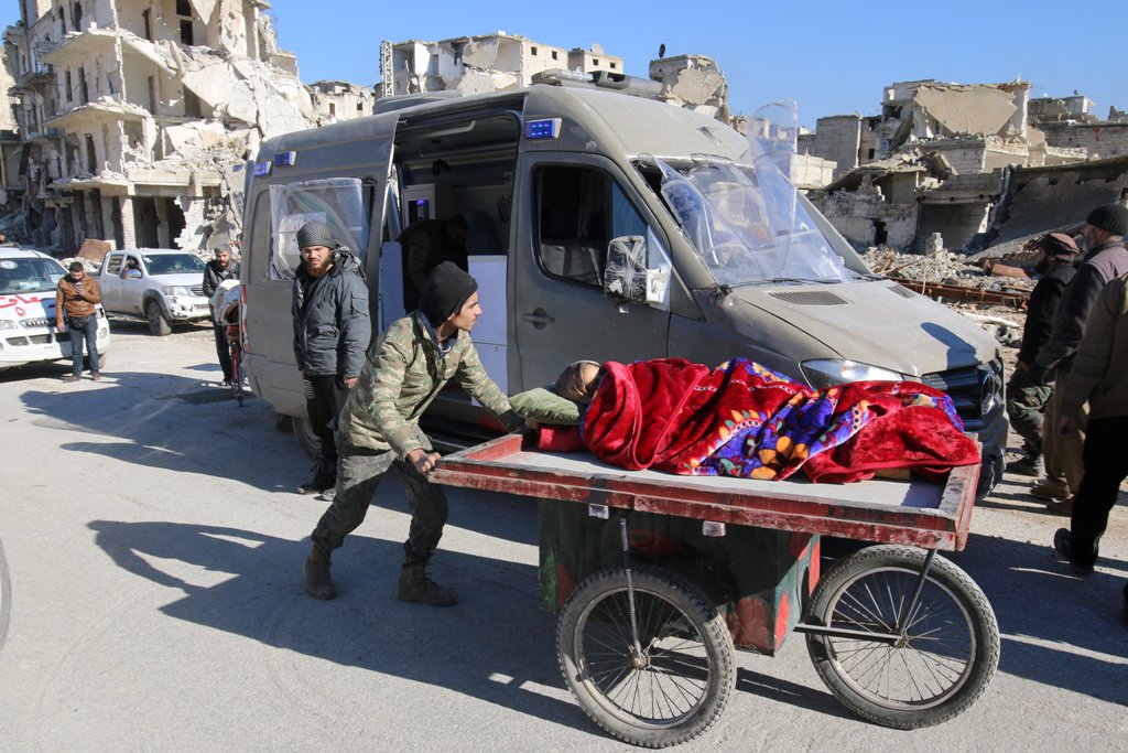 A man pushes a cart with a woman lying on it as vehicles wait to evacuate people from a rebel-held sector of eastern Aleppo, Syria December 15, 2016. REUTERS/Abdalrhman Ismail
